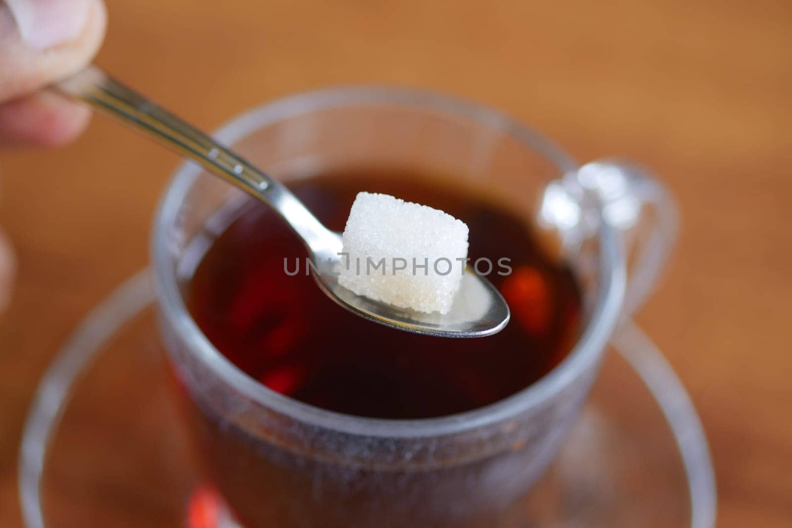 A small sugar cube delicately placed on a spoon, perfectly poised to sweeten a hot cup of tea