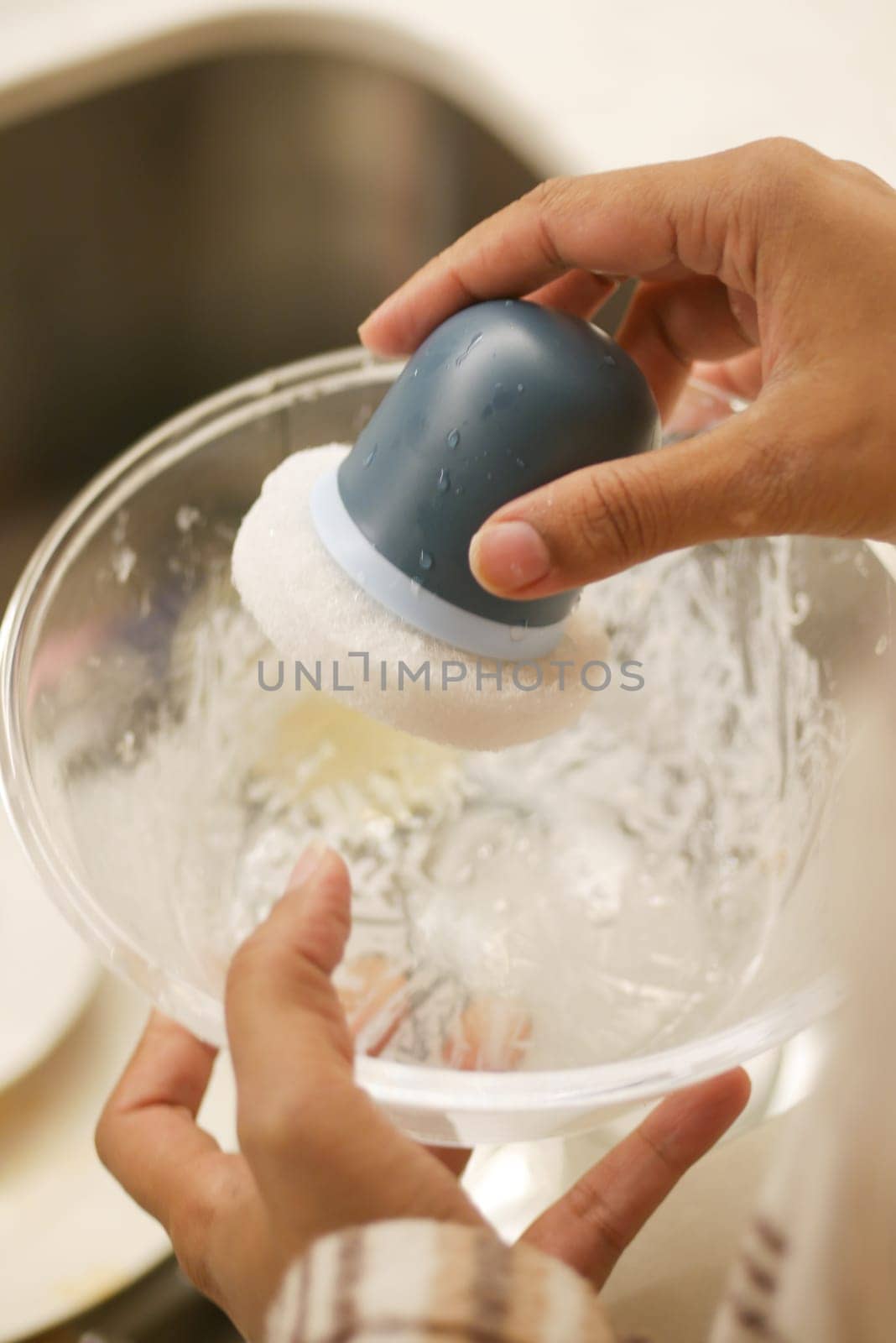 A person is scrubbing a bowl in a kitchen, ensuring cleanliness and hygiene standards