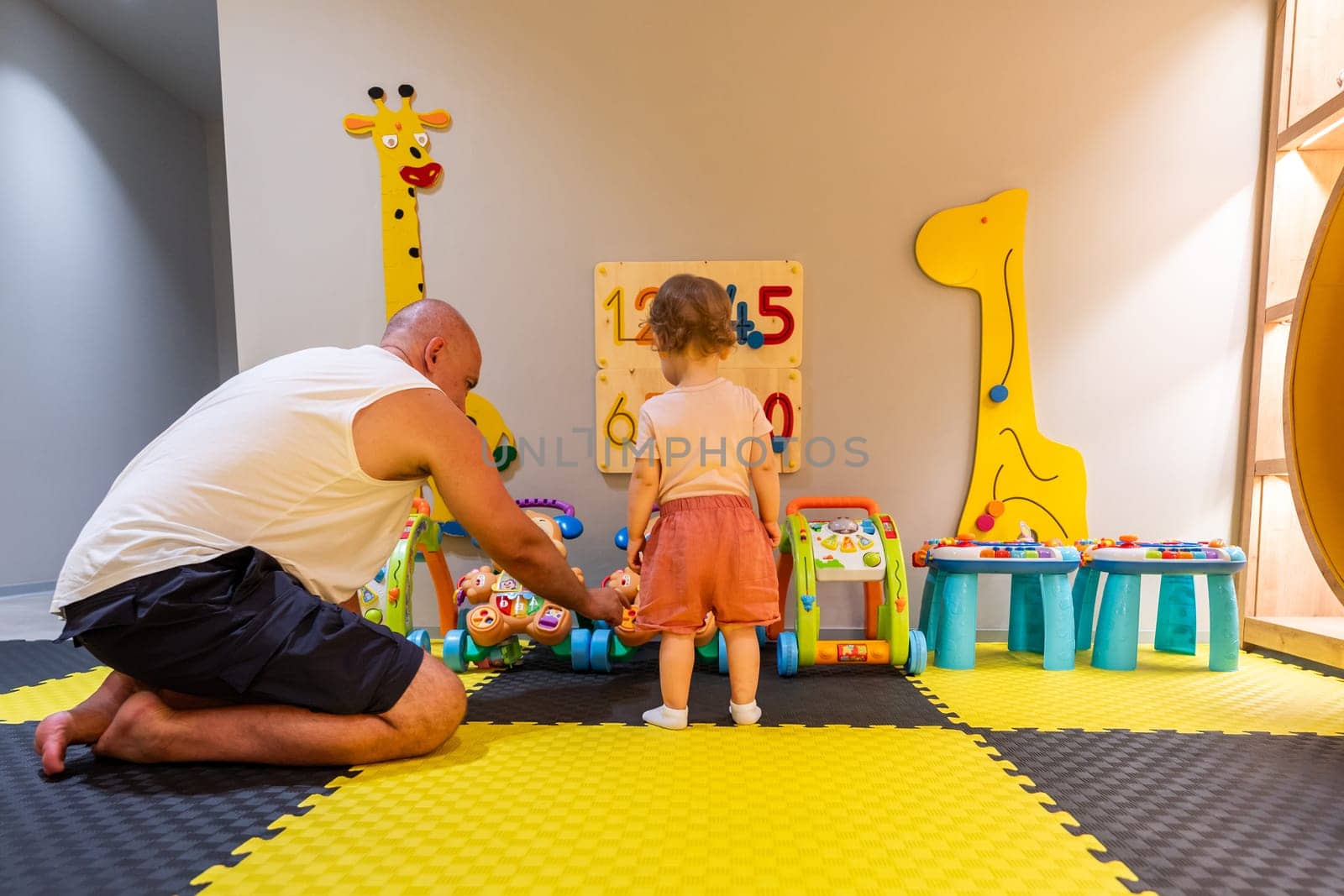 Father and child playing together in a colorful playroom with educational toys