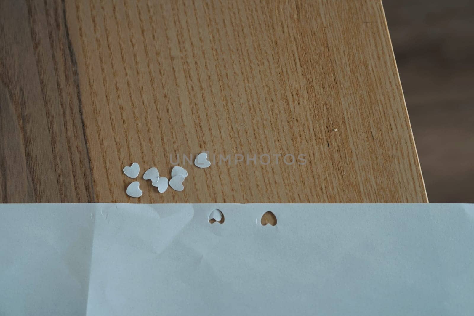 many small tiny white hearts made cut from paper on wooden table valentine day love symbol handmade . High quality photo