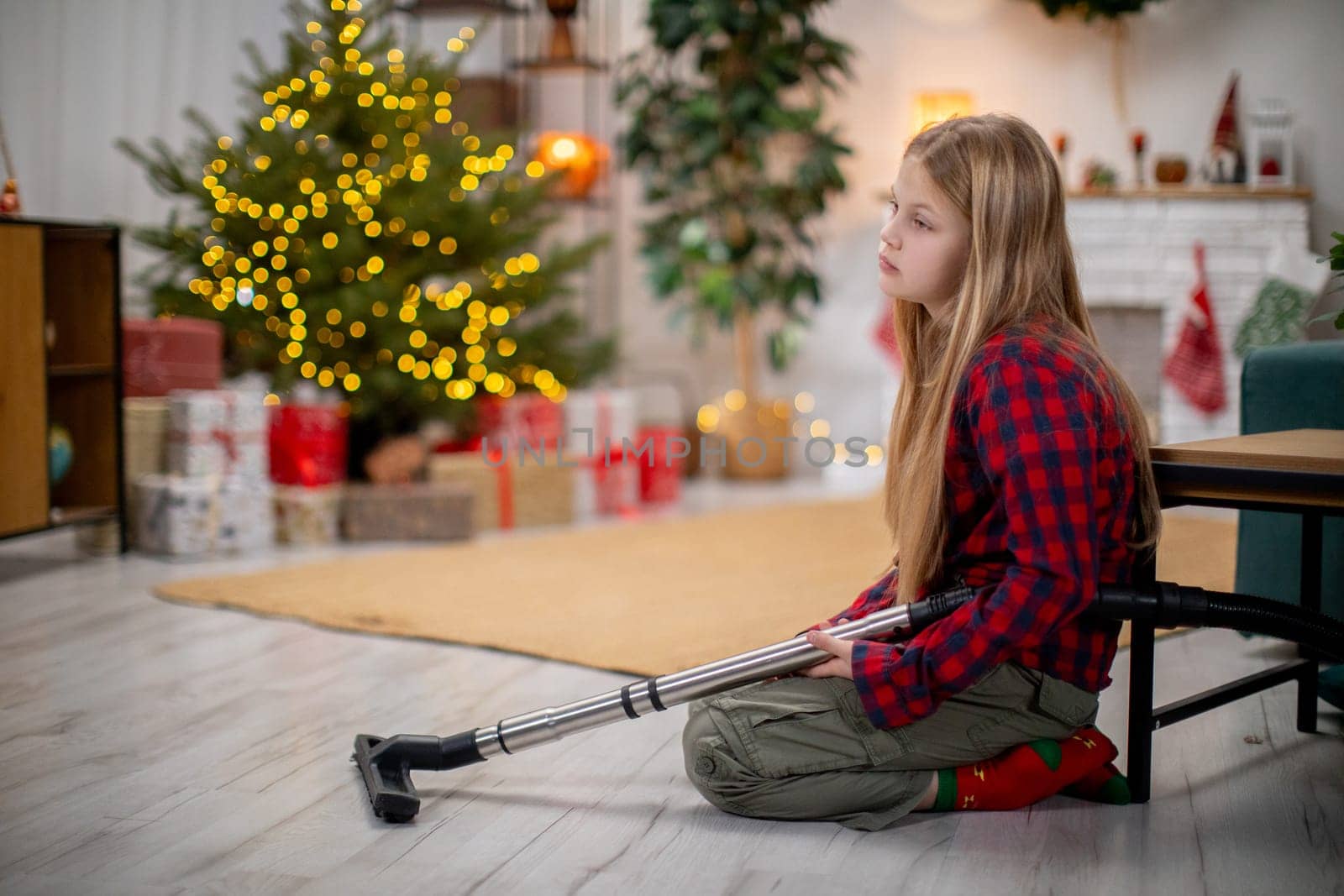 A thoughtful and reflective child who uses a crutch sits quietly beside a beautifully decorated Christmas tree