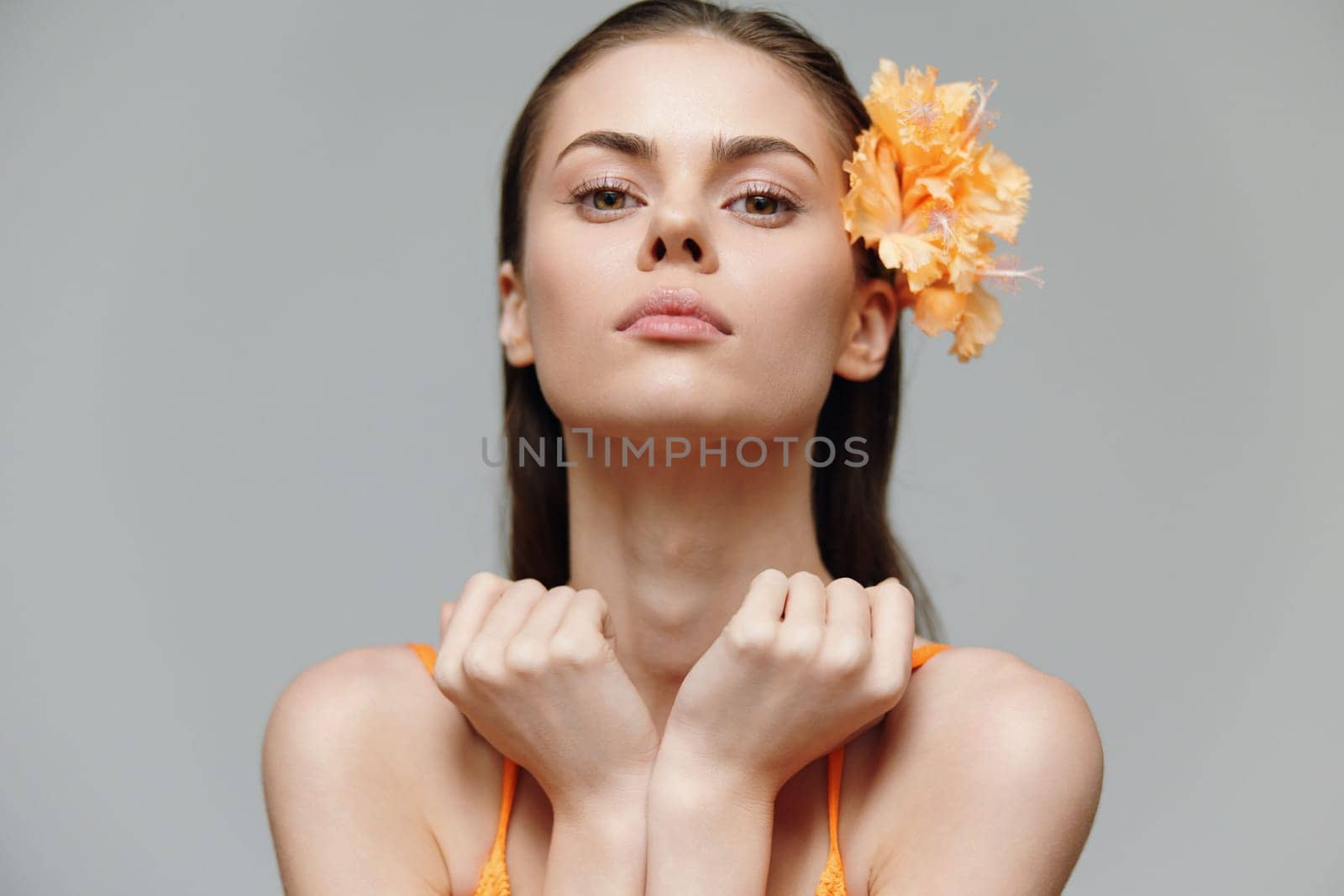 A stunning model wearing a vibrant orange outfit, exuding confidence with delicate, thoughtful emotions, suitable for fashion, beauty, and editorial themes.