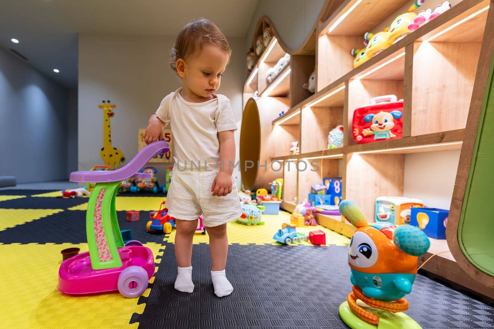 Young child having fun in a colorful playroom with educational toys and engaging activities. Concept of joyful play and early education