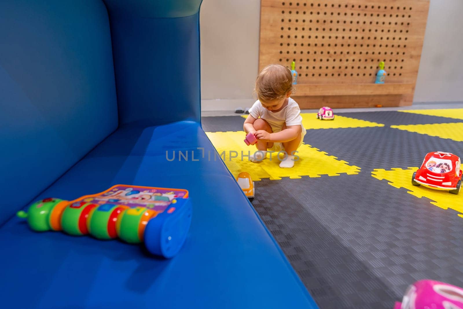 Baby exploring an interactive toy in a cheerful playroom filled with fun and learning opportunities. Concept of playful education and creativity for young children indoors