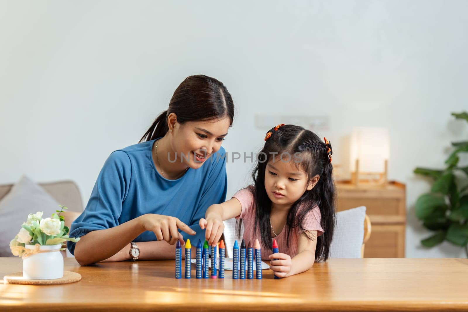 Happy family. Mother and daughter drawing together. Adult woman helping to child girl.