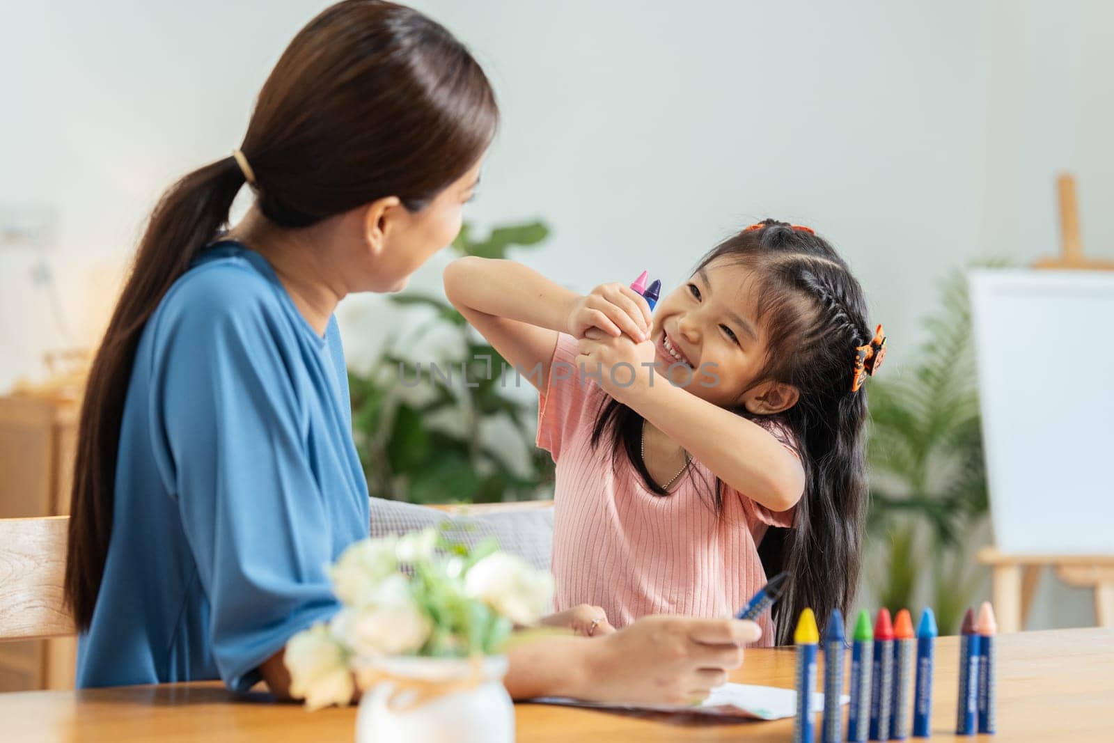 Happy family. Mother and daughter drawing together. Adult woman helping to child girl by itchaznong