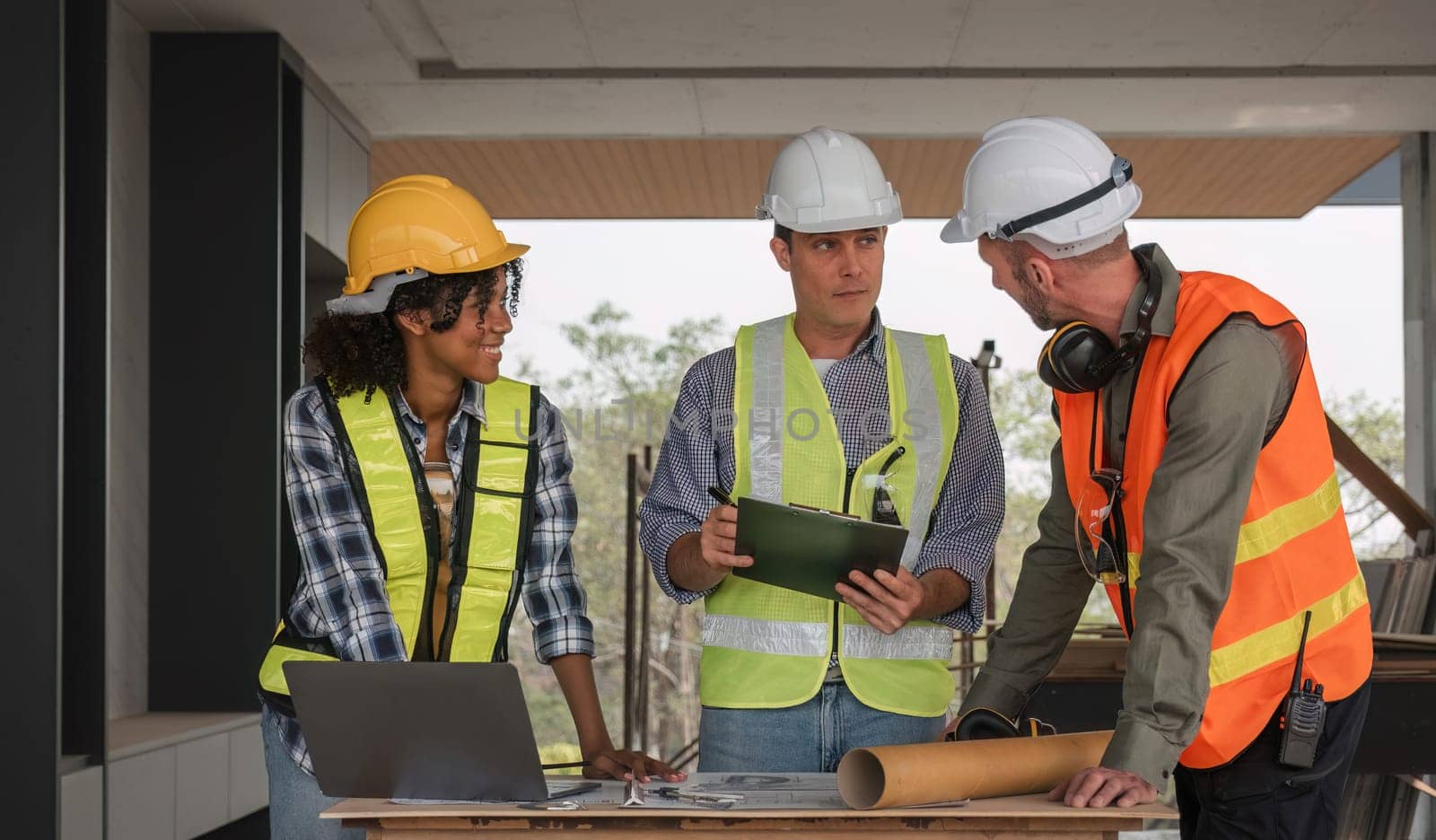 Diverse Team of Specialists Use Laptop on Construction Site. Real Estate Building Project with Engineer Investor and Businessman Checking Area, working on Civil Engineering, Discussing Strategy Plan by wichayada