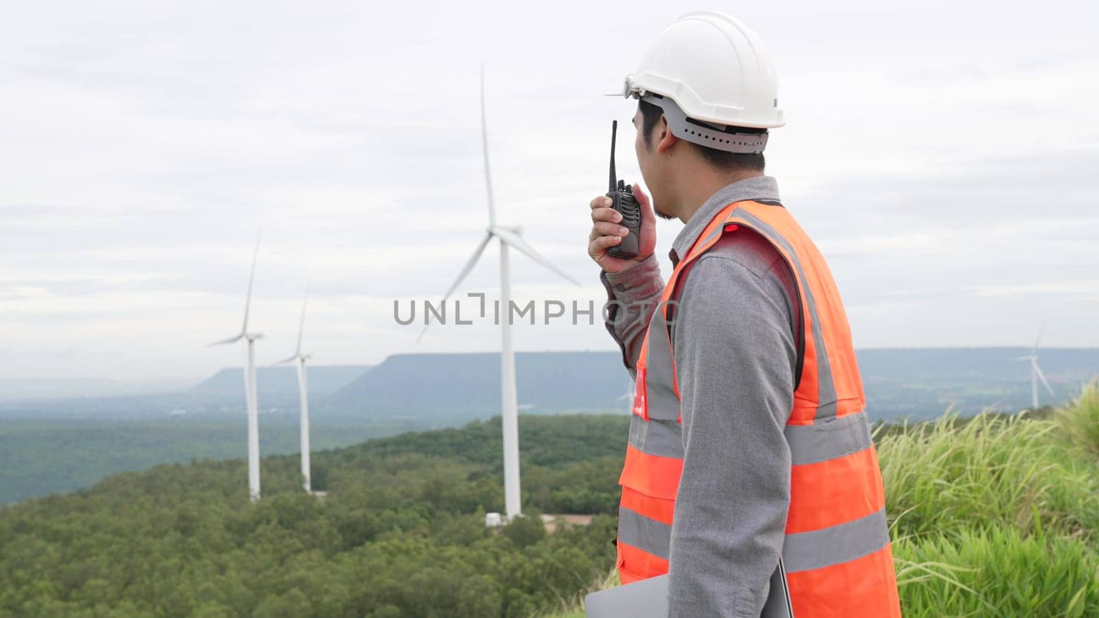 Progressive concept of engineer working in the wind farm atop of the mountain. by biancoblue