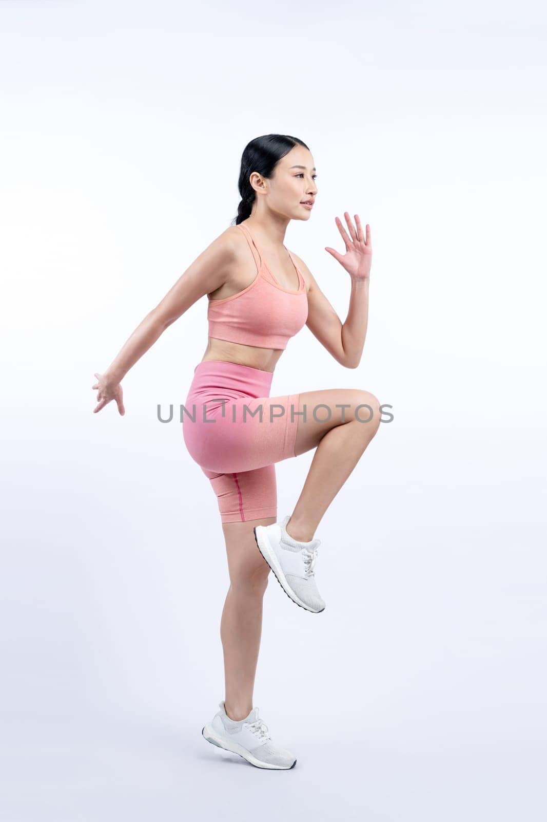 Side view young athletic asian woman on running posture in studio shot on isolated background. Pursuit of healthy fit body physique and cardio workout exercise lifestyle concept. Vigorous