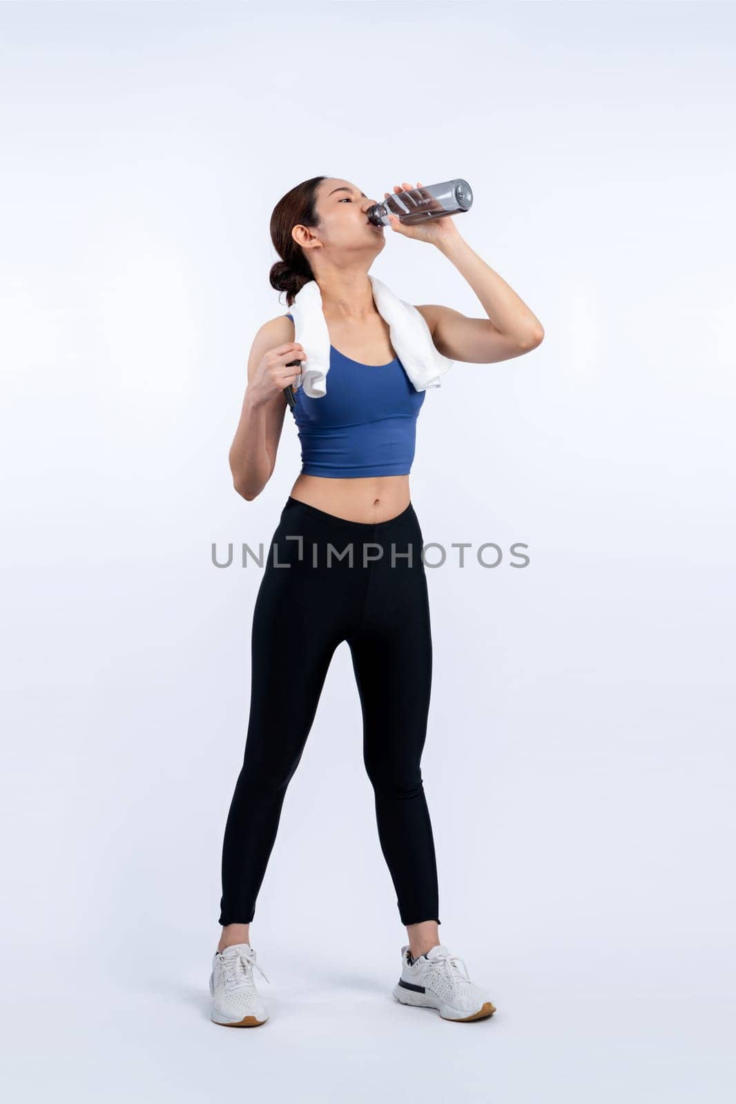 Athletic and sporty asian woman resting and drink water after intensive cardio workout training. Healthy exercising and fit body care lifestyle pursuit in studio shot isolated background. Vigorous