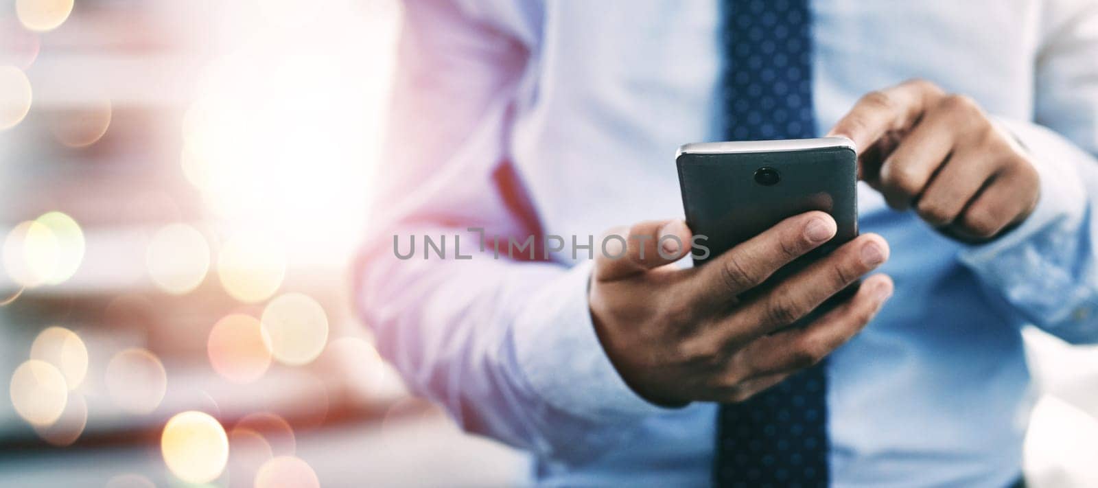 Businessman, phone and hands typing for communication or networking on bokeh background at office. Closeup of man on mobile smartphone app for online texting, chatting or social media and research by YuriArcurs