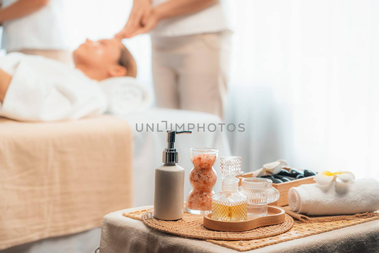Aromatherapy massage on daylight ambiance or spa salon composition setup with focus decor and spa accessories on blur woman enjoying blissful aroma spa massage in resort or hotel background. Quiescent