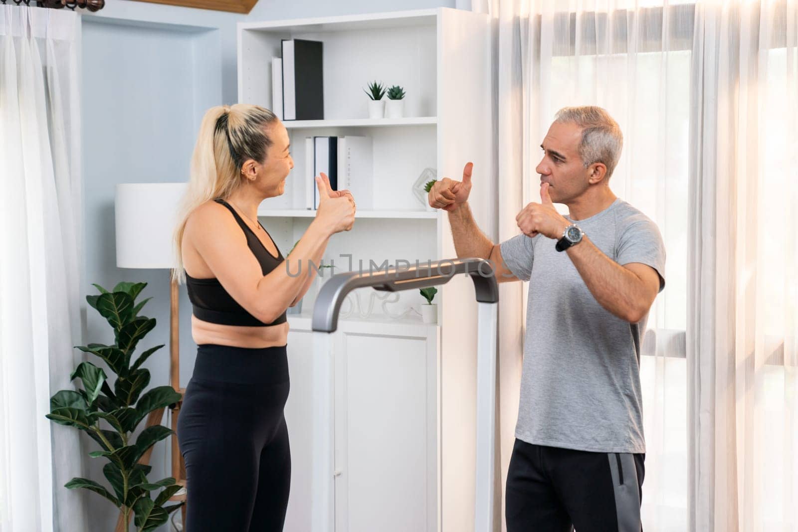 Athletic and sporty senior couple portrait in sportswear with successful or celebrating after overcome struggle posture as home exercise concept with healthy fit body lifestyle after retirement. Clout