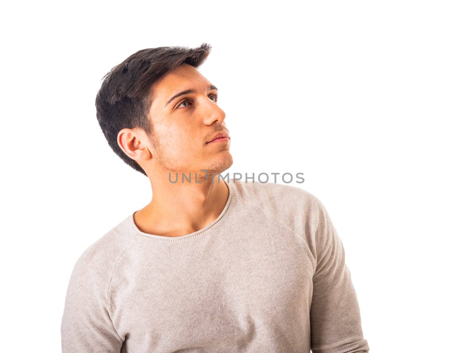 A man in a gray shirt is looking up to a side, isolated on white background in studio