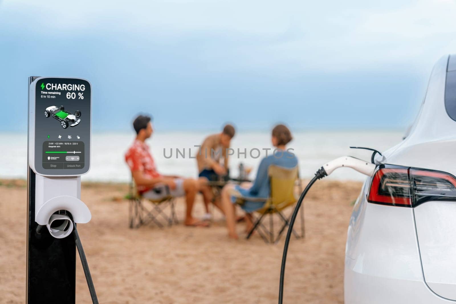 Alternative family vacation trip traveling by the beach with electric car recharging battery from EV charging station with blurred family enjoying the seascape background. Perpetual