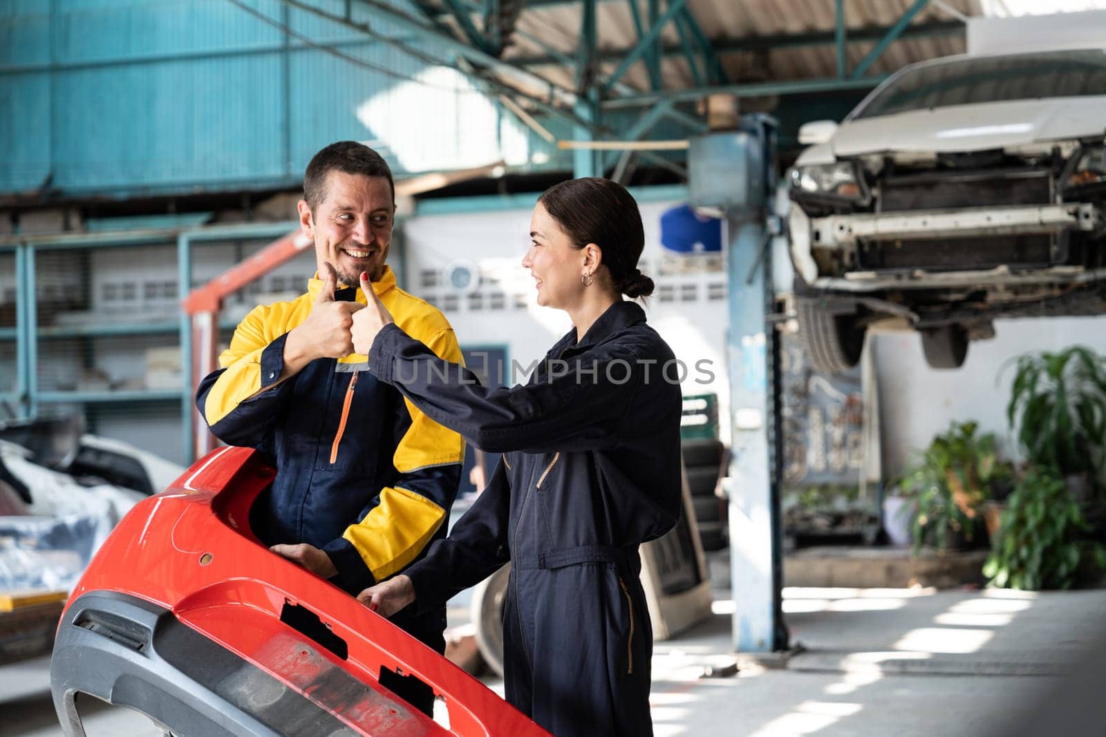 Two happy vehicle mechanic celebrate and high five after made successful car inspection or repair in automotive service car workshop. Technician team enjoy accomplishment together in garage. Oxus