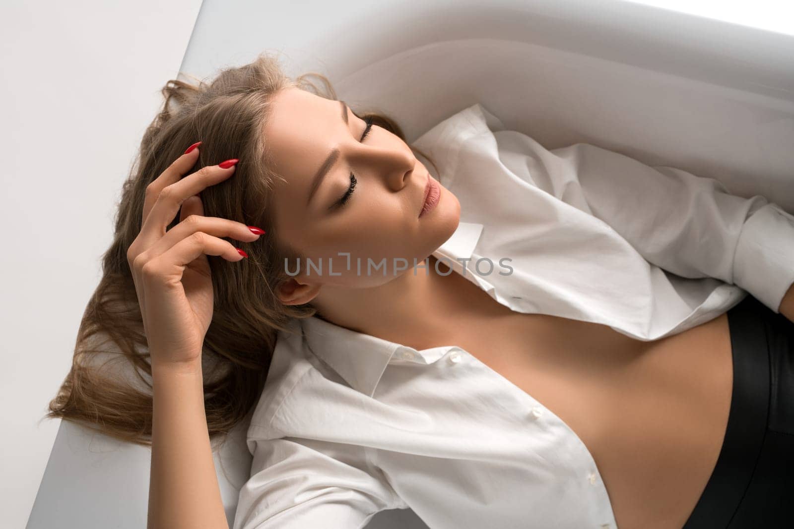 Beautiful woman wearing unbuttoned white shirt in the bath high angle view