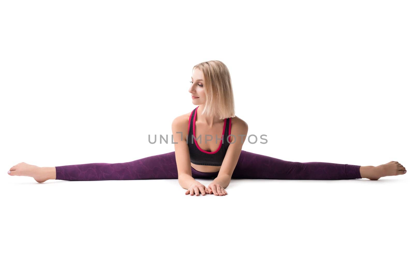 Attractive young blonde woman working out and doing leg split exercise isolated on white background