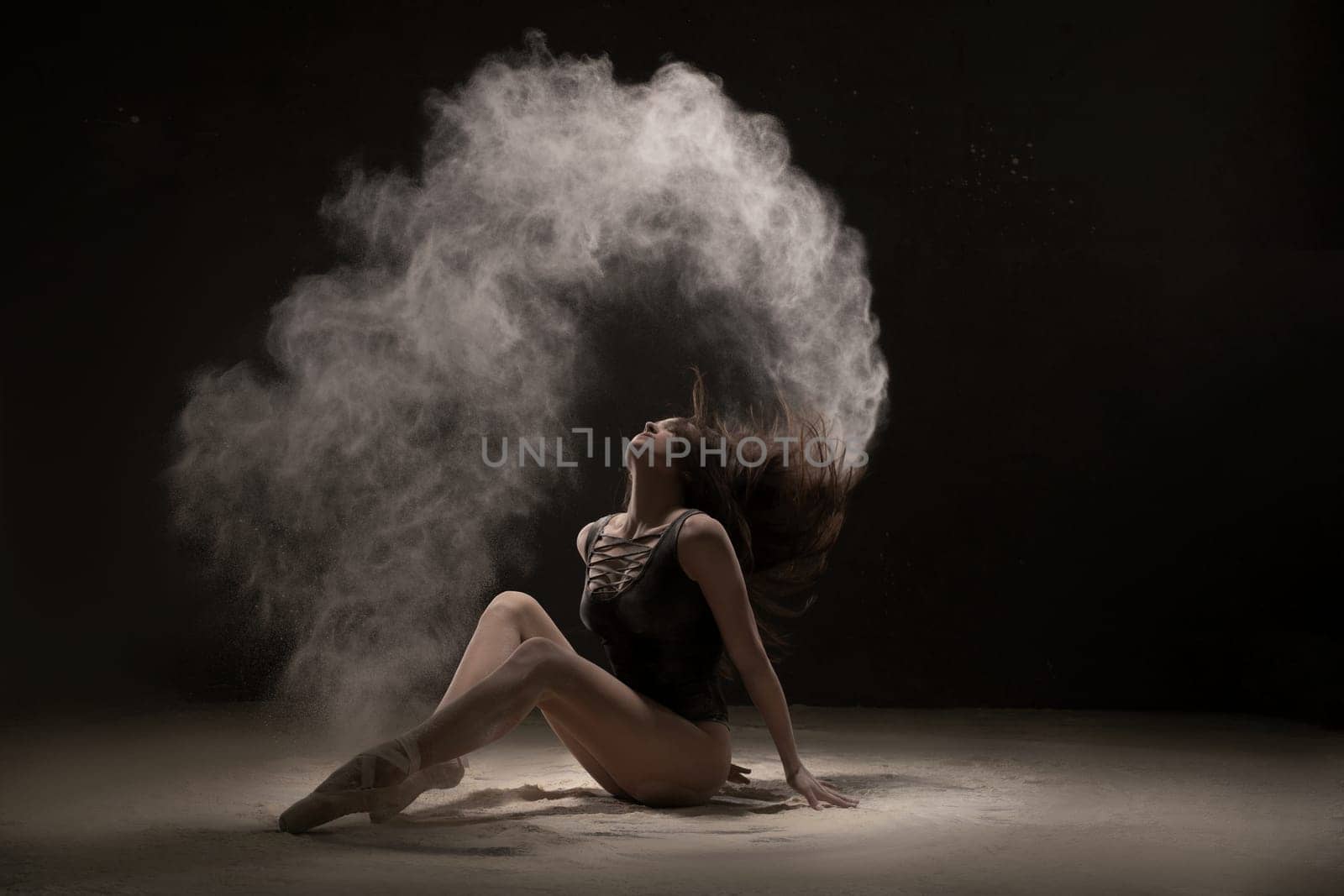 Brunette on the floor in white dust cloud shot in the dark room