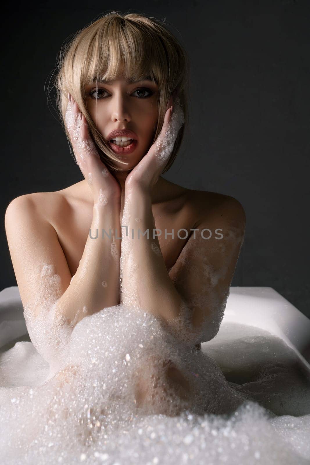 Nude blonde having bath in white foam portrait