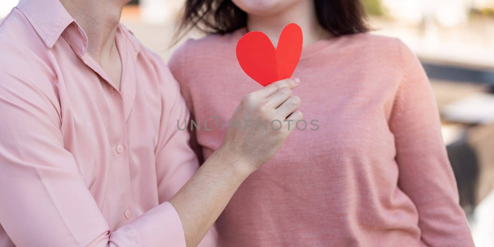 A couple shares a tender moment holding a heart symbol to celebrate their love during Valentine's Day.