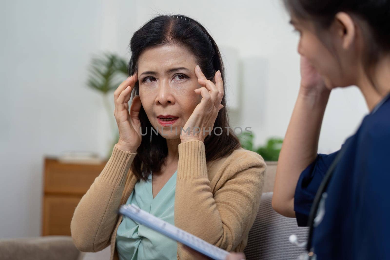 An elderly woman seeks advice from her caregiver and a healthcare team for her health concerns in a clinic setting.