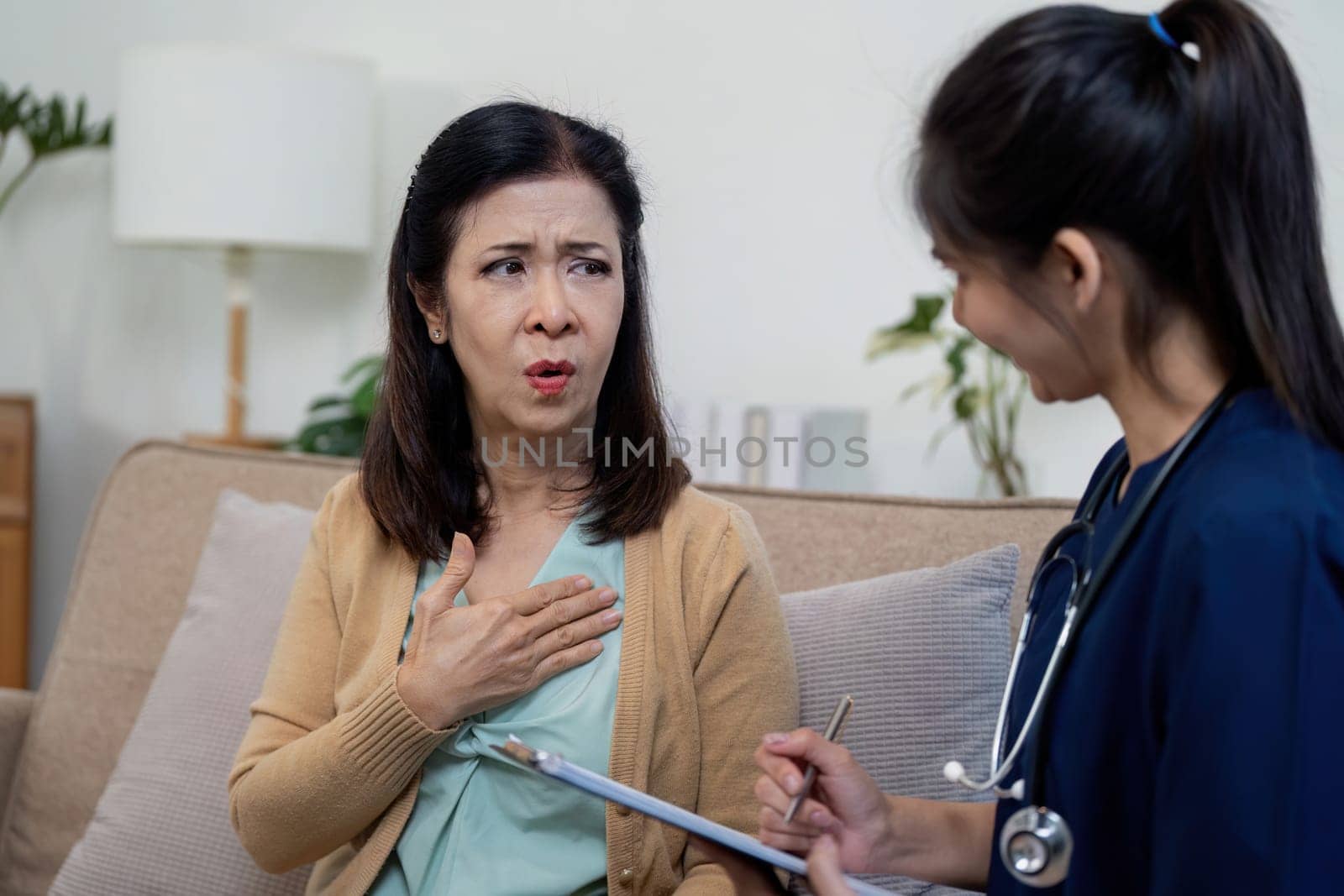 A nurse attentively listens to an elderly patient concerns in a warm home setting.