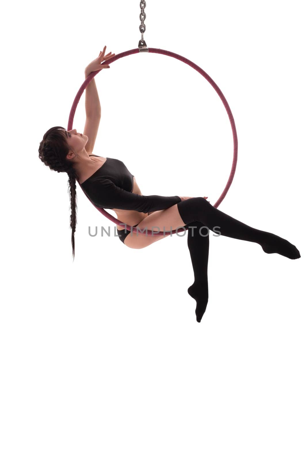 Side view of beautiful charming gymnast sitting on hung hula hoop on white background