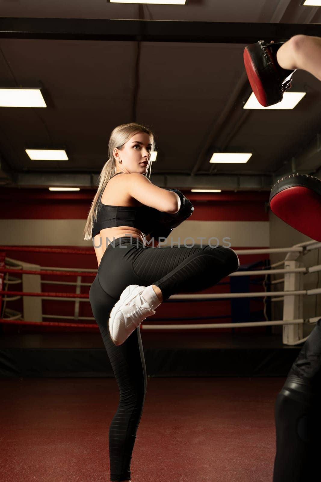 Young blonde in boxing gloves fighting with a man in a sports gym gym