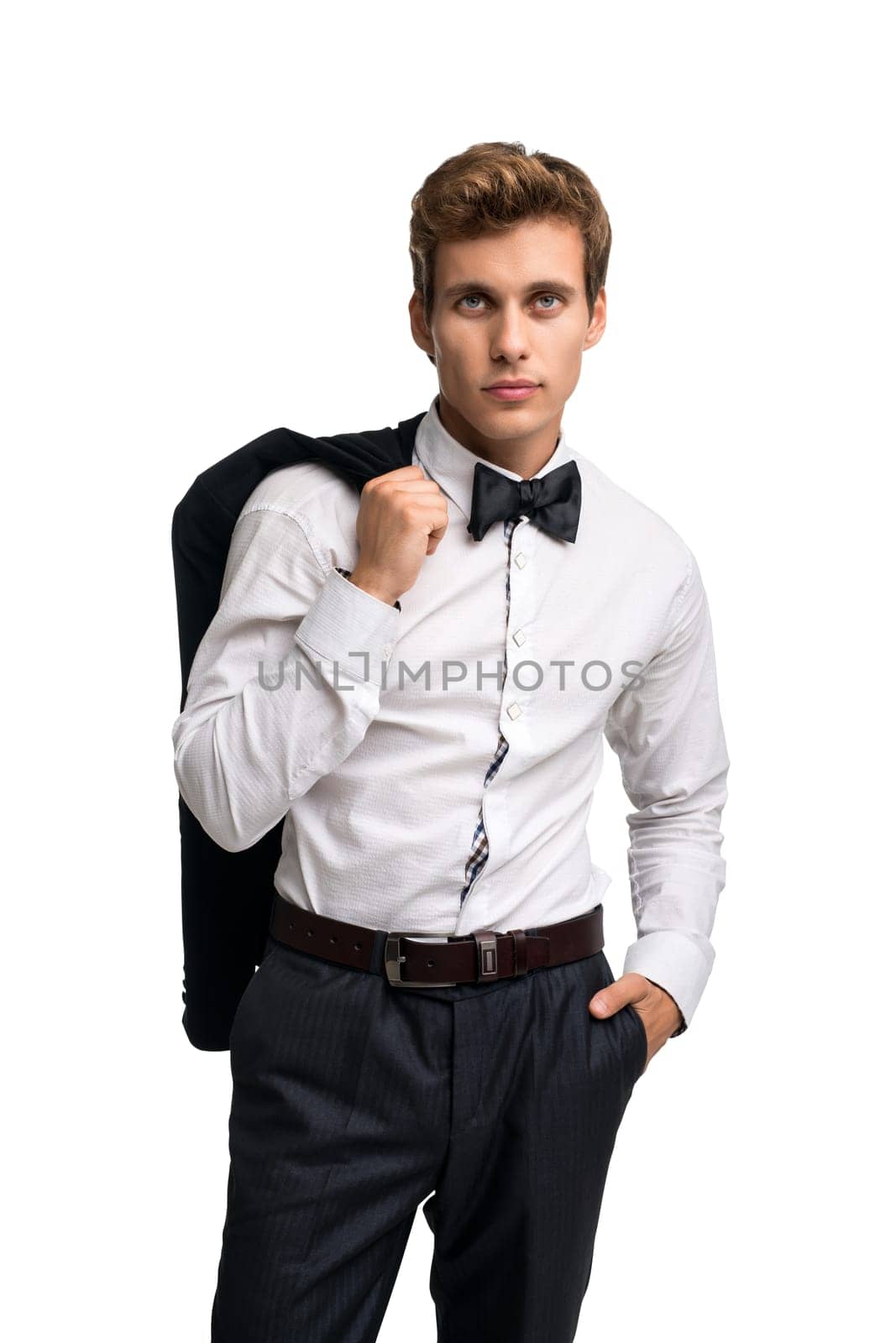 Elegant young man in white shirt standing holding coat over shoulder and looking at camera on white background
