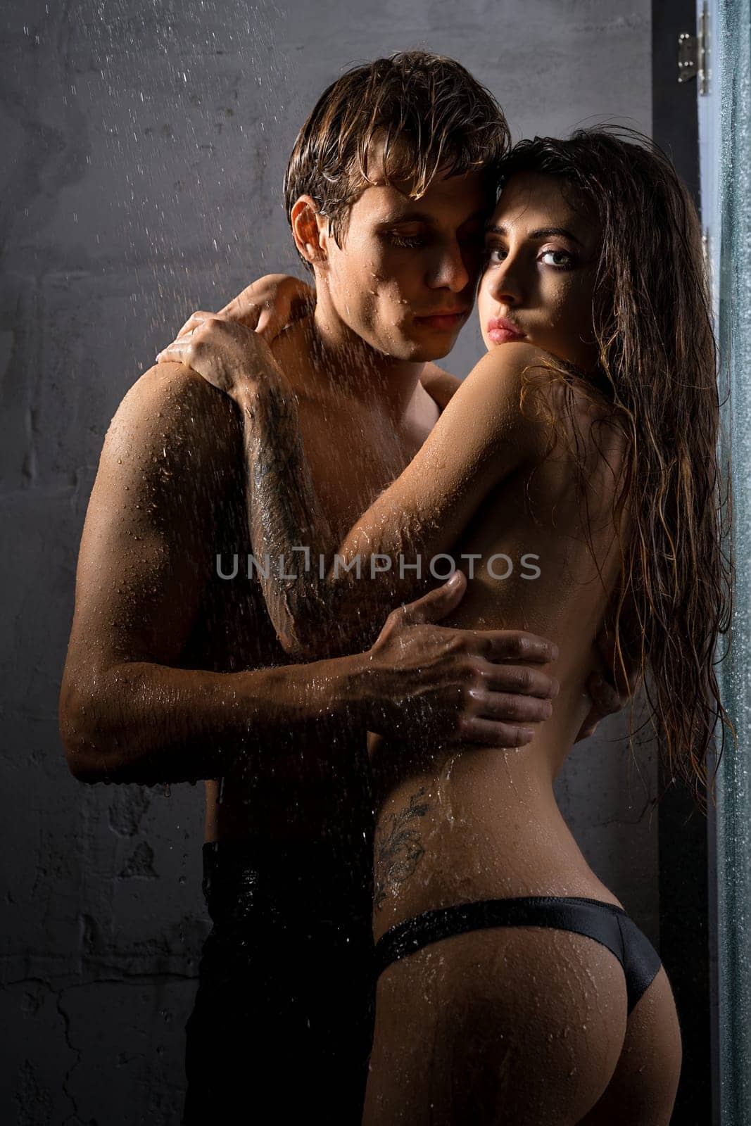 Shirtless man and girl topless embracing in shower view