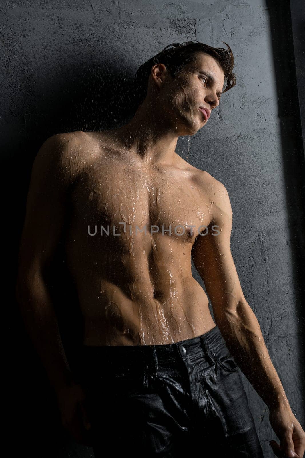 Shirtless muscular man wearing only jeans cropped view in shower