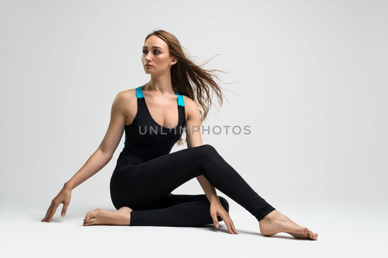 Beautiful blonde in black and blue sportswear sitting on the floor view