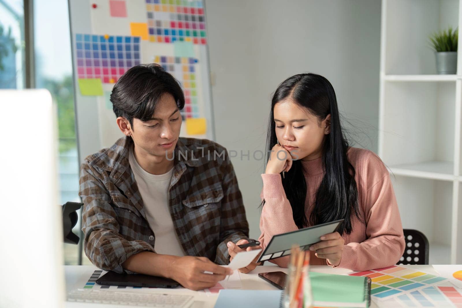 A team collaborates on design projects in a vibrant workspace showcasing creativity and teamwork in graphic development.