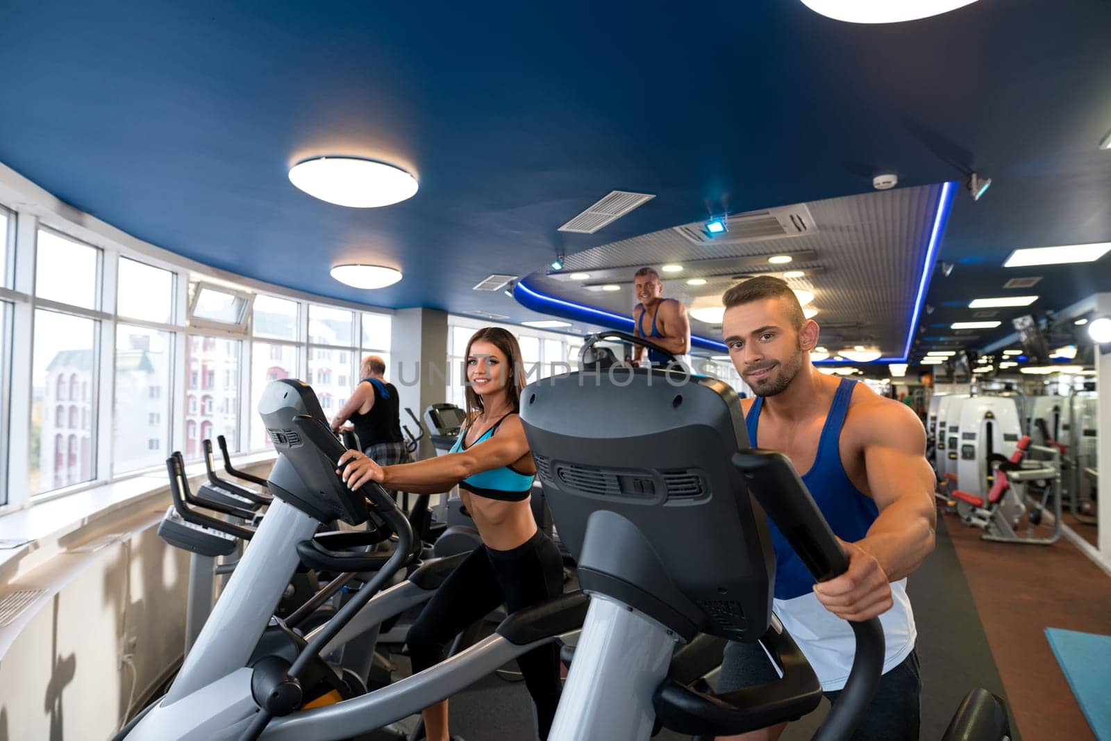 Young beautiful couple exercising on simulators in a gym