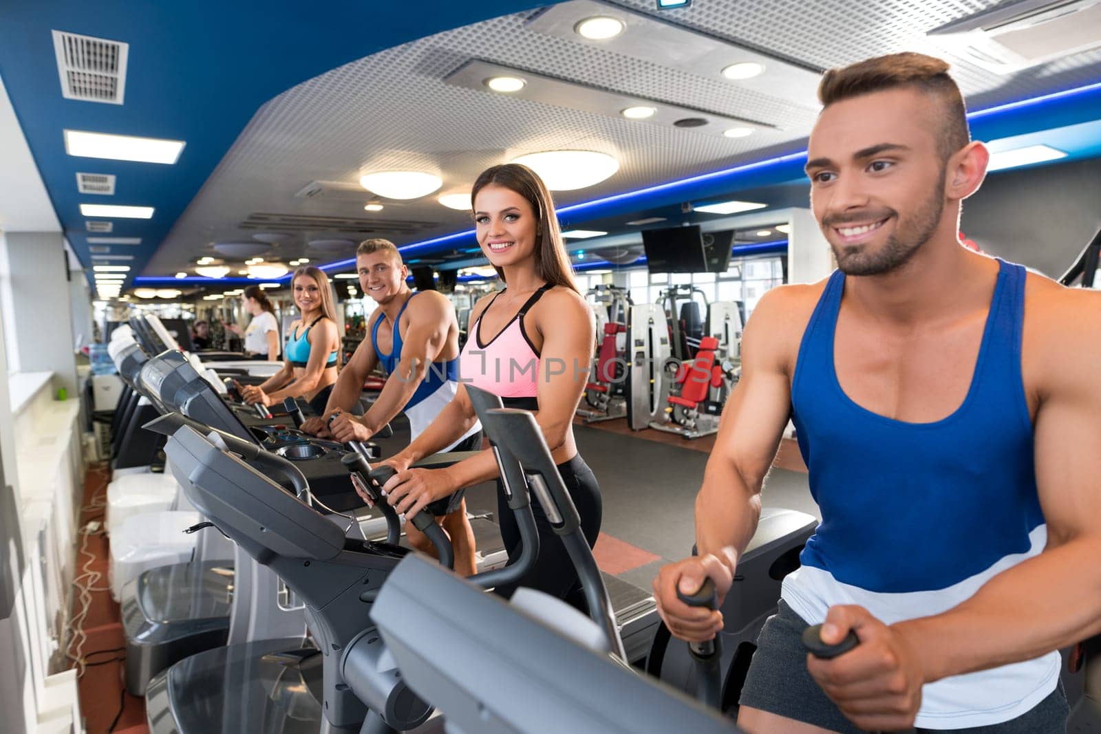 Young sporty people exercising on simulators in a gym