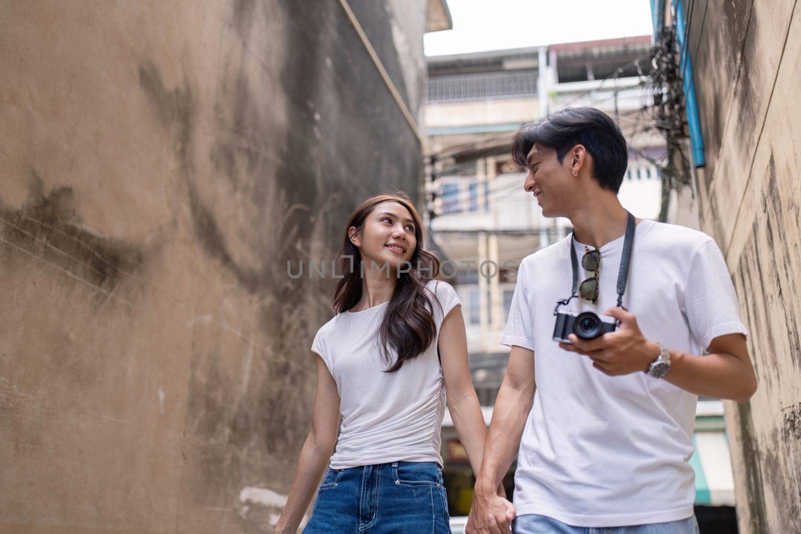 A couple explores a vibrant urban alley capturing memories together with their camera while enjoying their travel adventure.