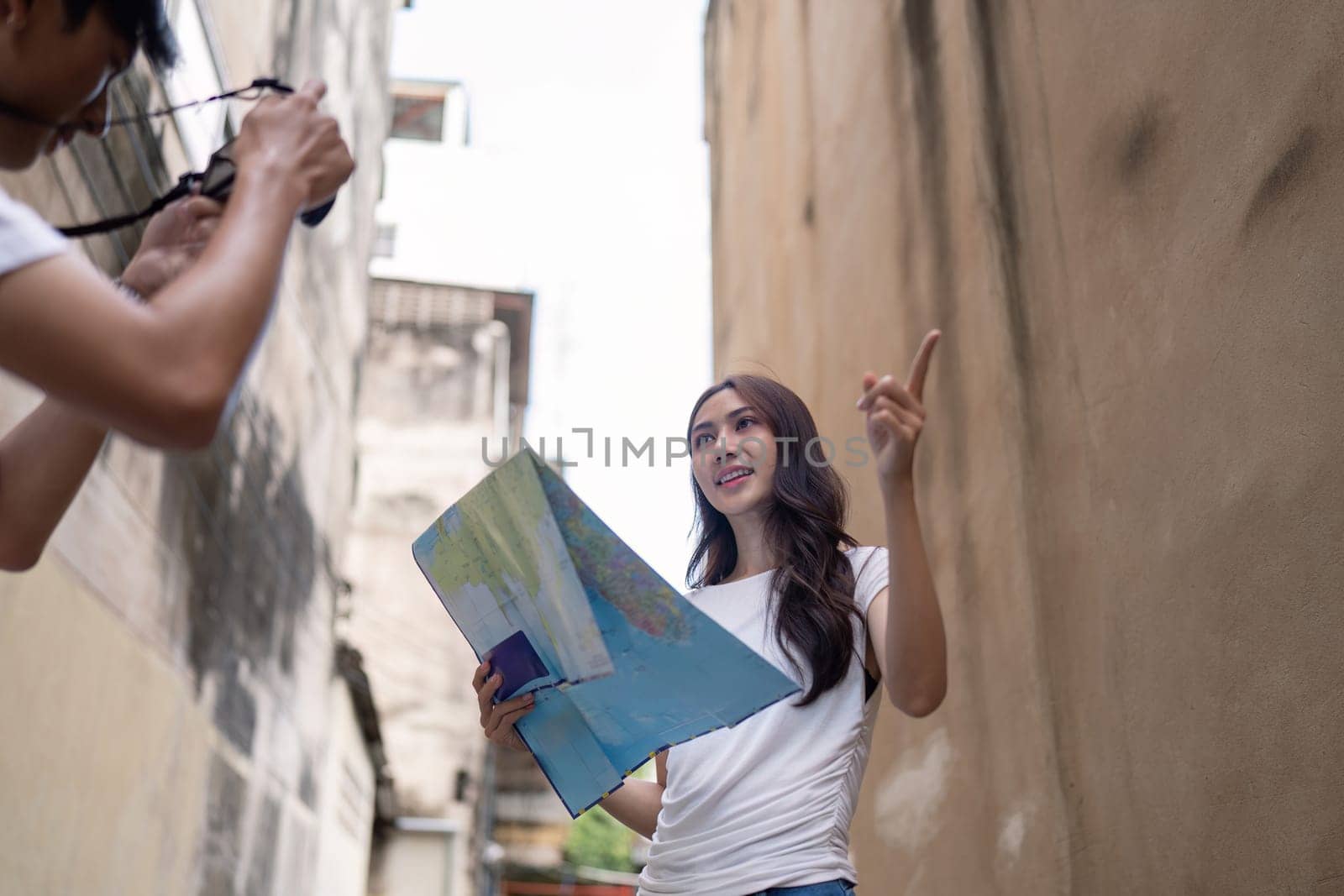 A couple enjoys their travel adventure an urban alley while capturing memorable moments on camera.