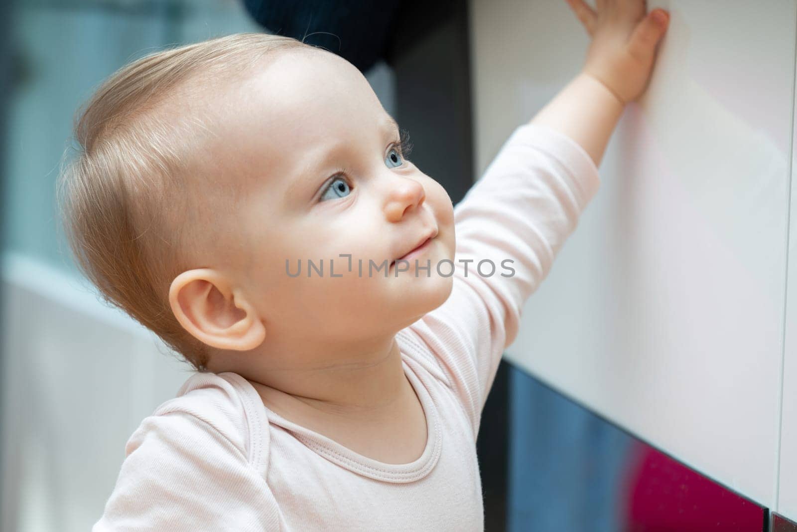 Joyful baby reaching upward with a curious expression