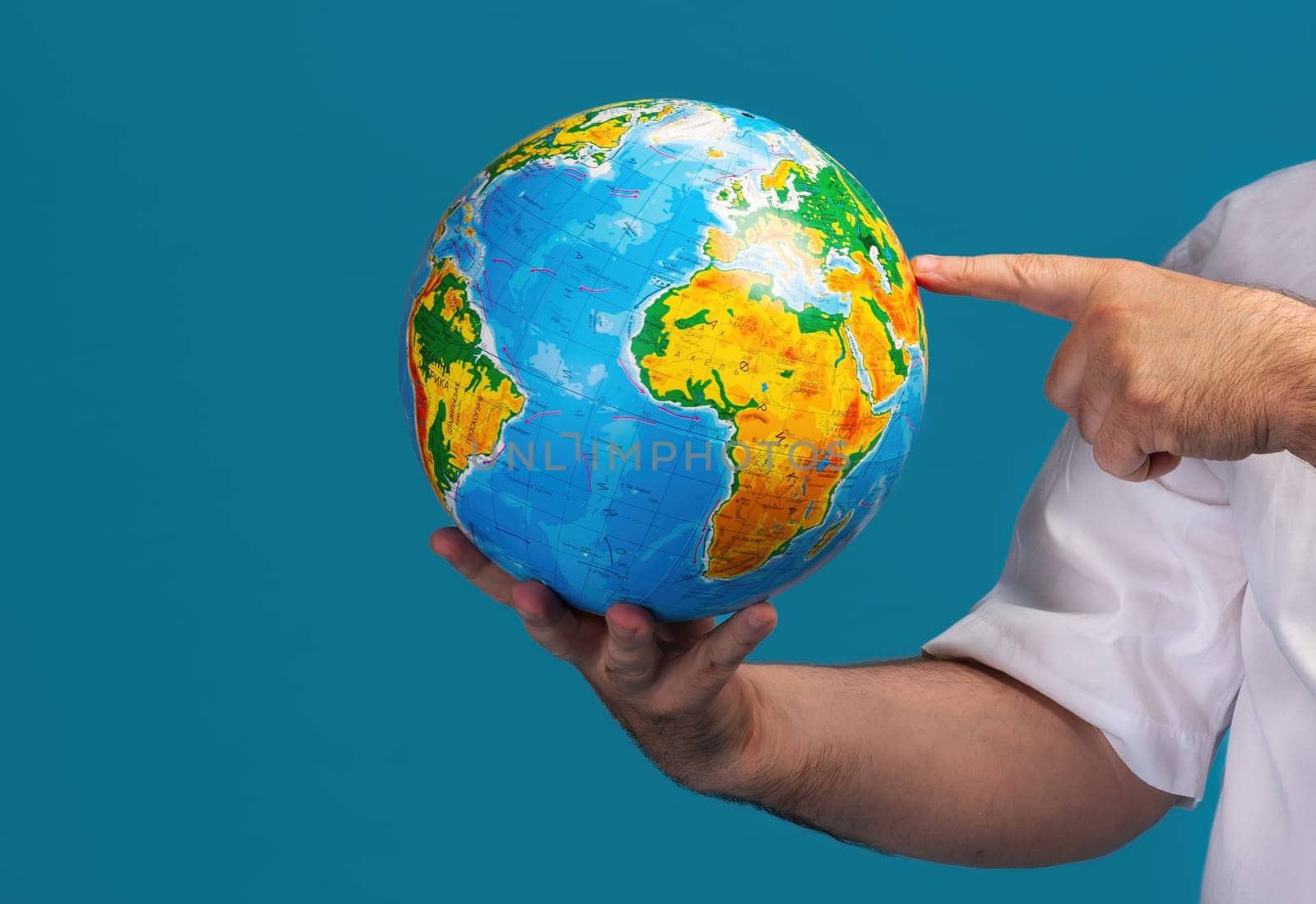 An individual holds a globe and points at a specific location, emphasizing the significance of geography and global exploration. The bright colors of the globe make it visually engaging.