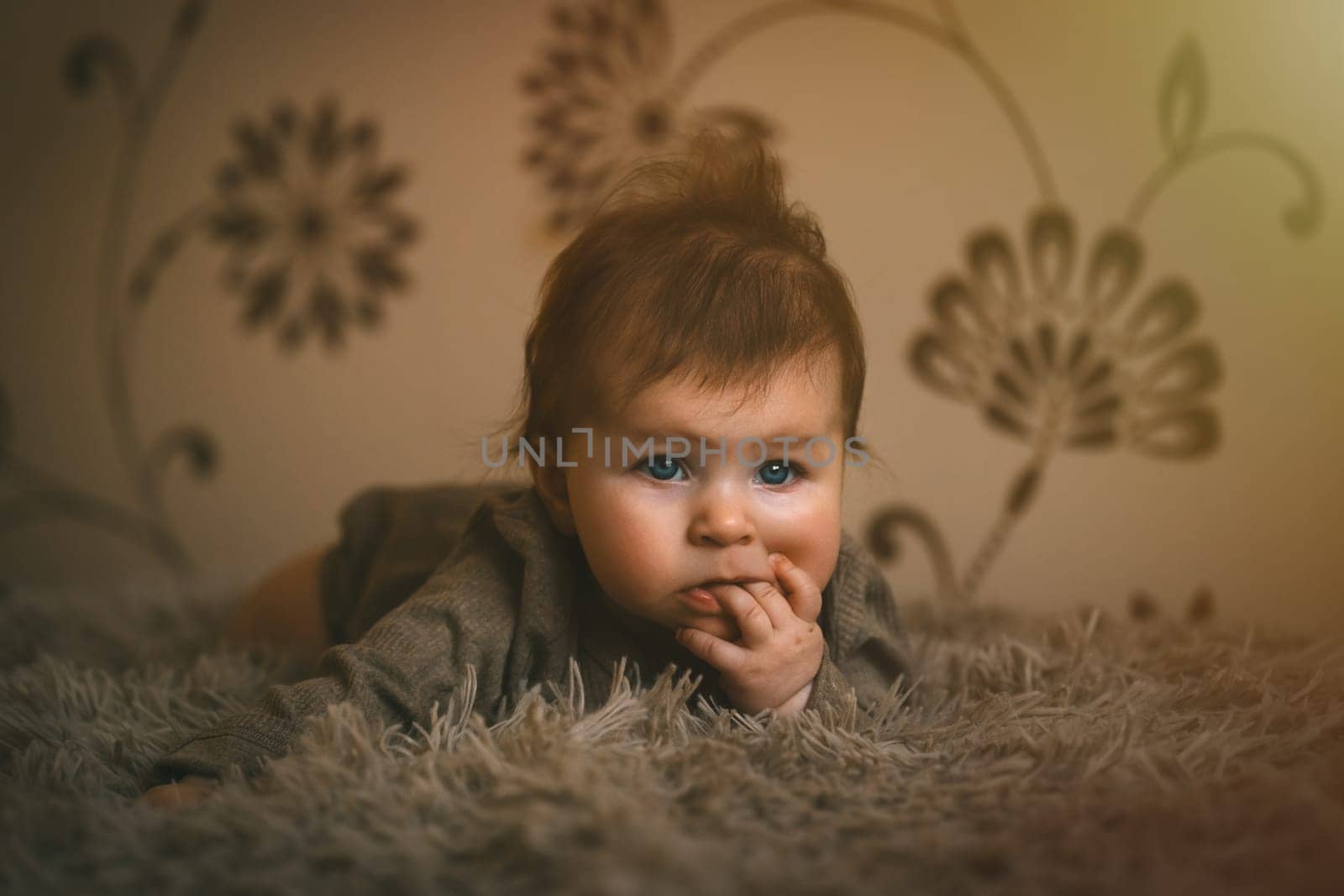 Cute baby girl in brown clothes close up crawling on bed. Adorable kid portrait. 5 month old child. High quality photo