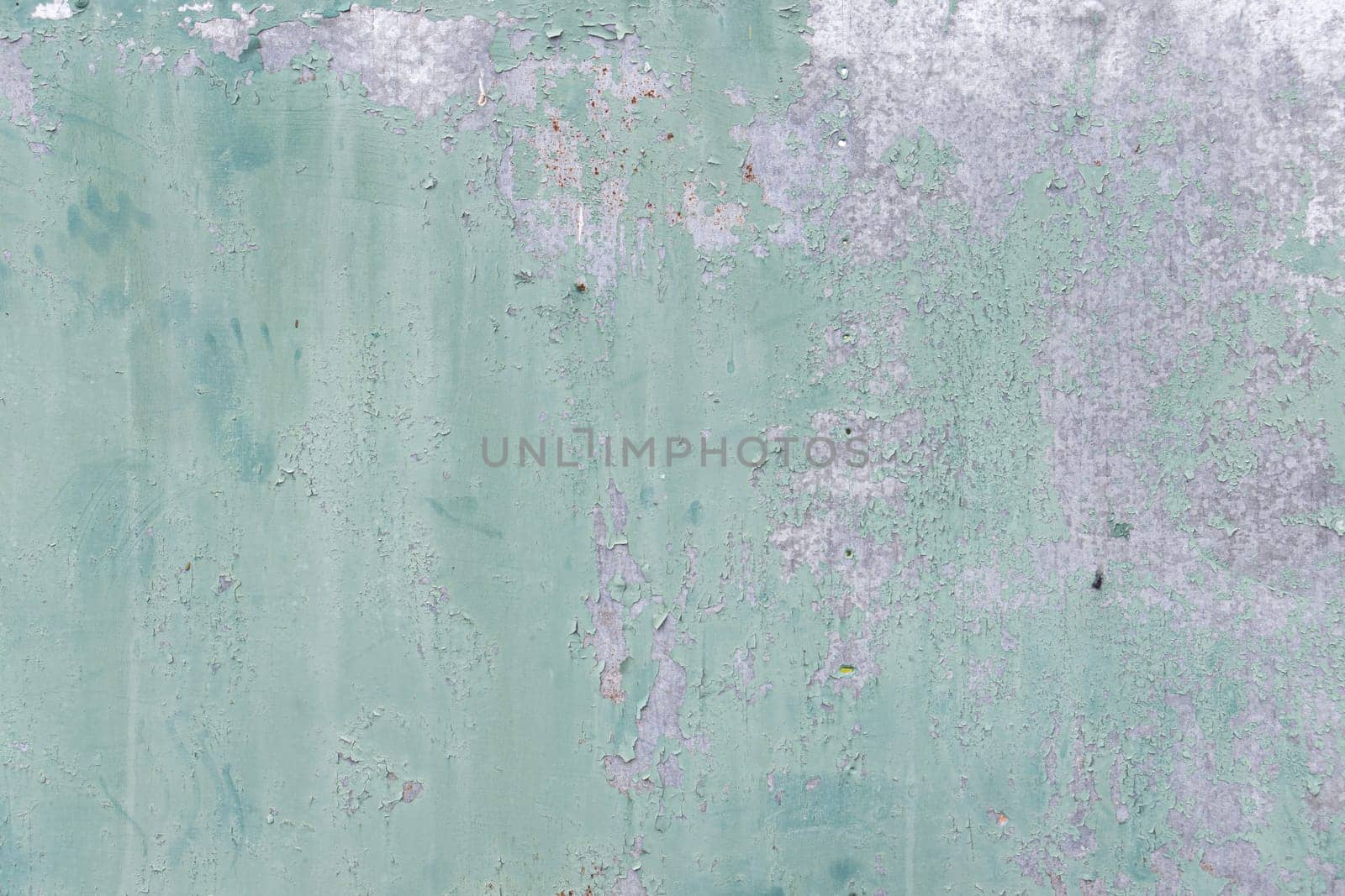 A light green wall with weathered paint and subtle textures, showcasing peeling areas and an aged aesthetic with a focus on detail.