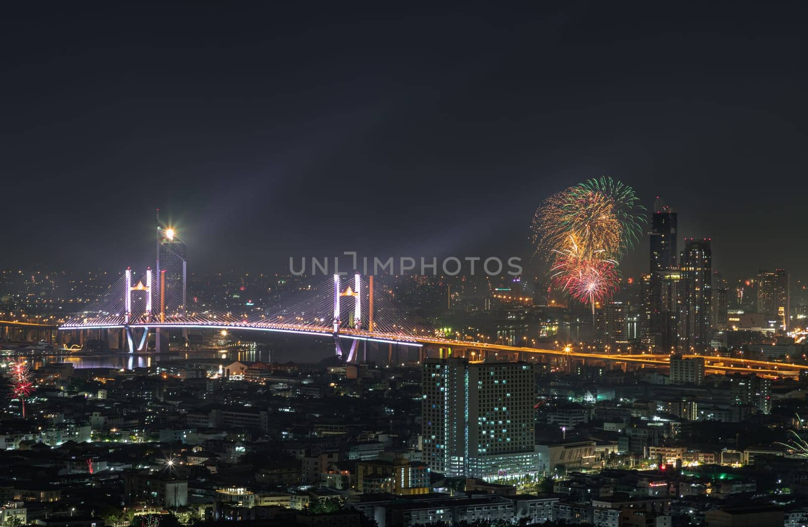 Bangkok, Thailand 31 Dec, 2024 - Night view of Skyscrapers with Colorful fireworks light up sky over Thotsamarachan Bridge (Rama IX Bridge) crossing Chao phraya river. Beautiful city of Bangkok with bright glowing lights of New Year celebration fireworks, use it as your Wallpaper, Poster and Space for text, Selective focus.