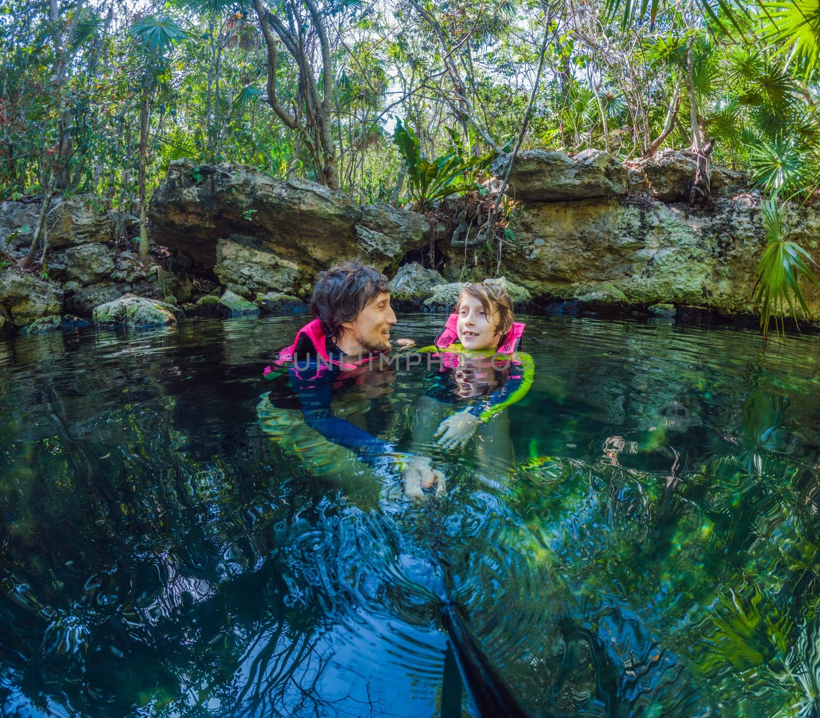 09.12.24, Playa Del Carmen, Mexico: Father and son tourists in the water of a cenote at Xcaret park wearing marked life jackets. Mexican tourism in natural parks. Family bonding, eco-tourism, and adventure concept in Quintana Roo.