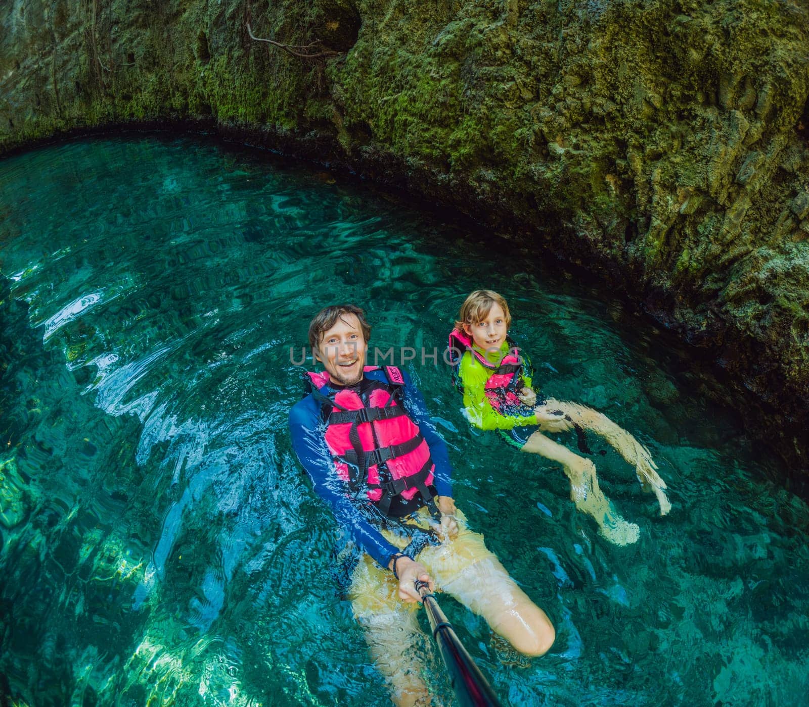 09.12.24, Playa Del Carmen, Mexico: Father and son tourists in the water of a cenote at Xcaret park wearing marked life jackets. Mexican tourism in natural parks. Family bonding, eco-tourism, and adventure concept in Quintana Roo.