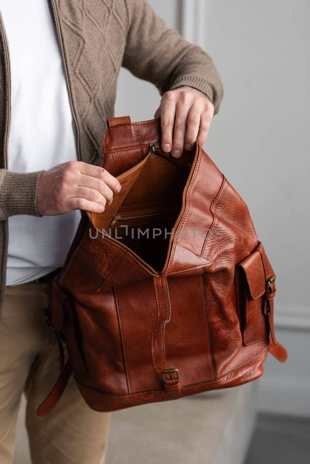 A fashionable man stands with a yellow brown backpack in a contemporary room, embodying urban style and professionalism.
