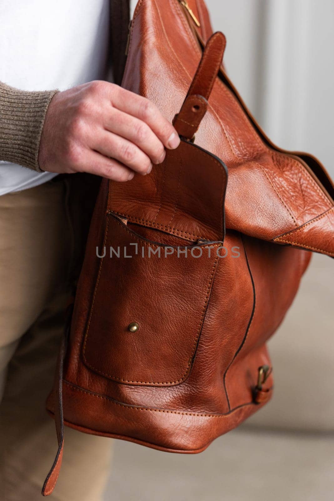 A fashionable man stands with a yellow brown backpack in a contemporary room, embodying urban style and professionalism.