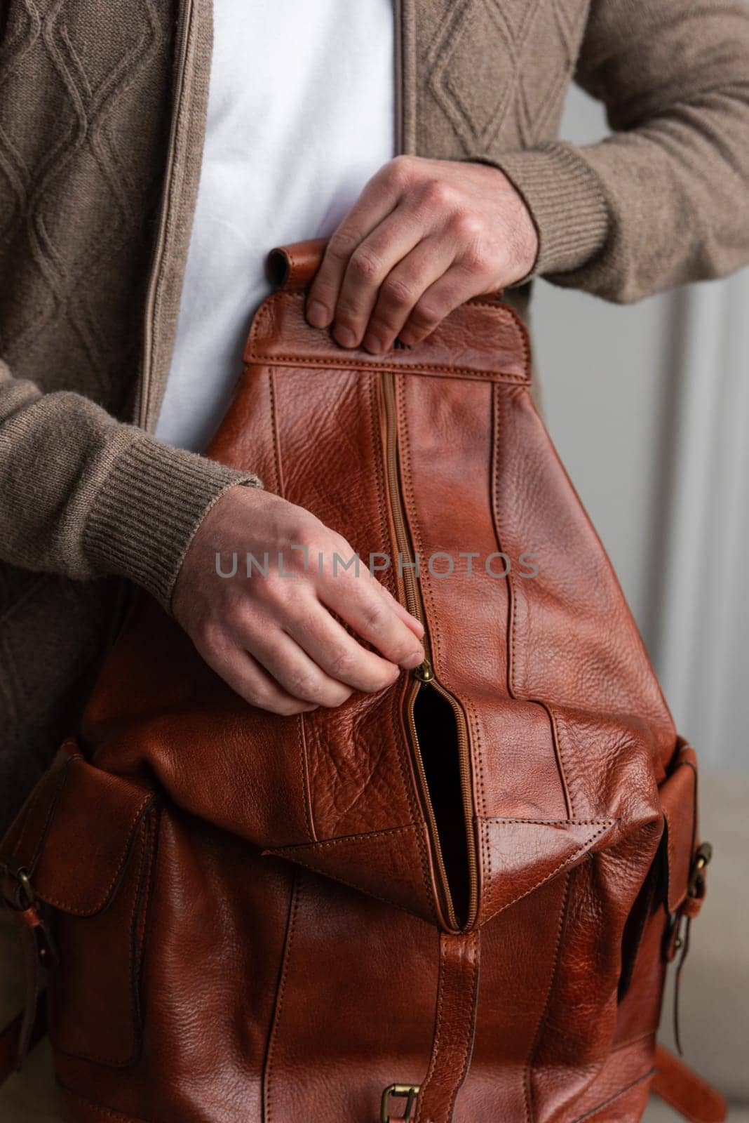 A fashionable man stands with a yellow brown backpack in a contemporary room, embodying urban style and professionalism.