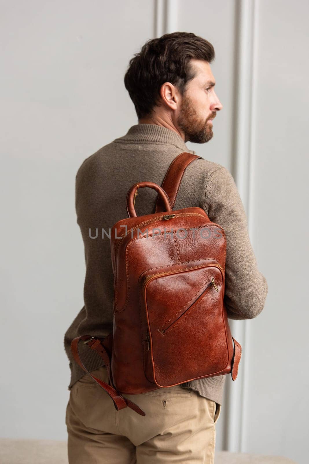 A fashionable man stands with a yellow brown backpack in a contemporary room, embodying urban style and professionalism.
