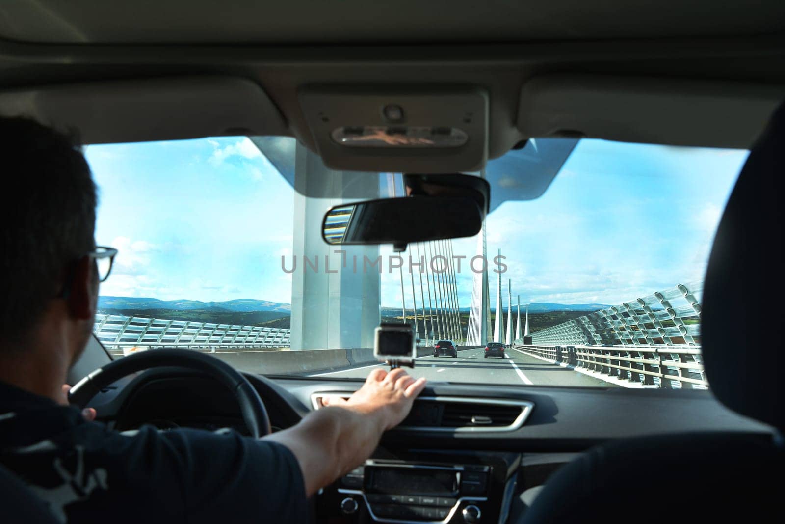 A man in a car traveling on a modern bridge